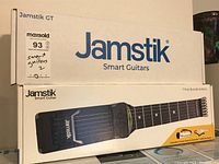 Stacked boxes of Jamstik GT and Smart Guitar showing brand logo and model name