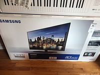 Front of unopened Samsung TV retail box showing product image and branding