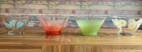 Front view of four serving bowls showing varying Mid Century colorful designs and shapes.
