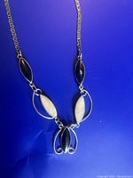 Front view of the necklace showing black onyx and pearl-like stones set in silver with decorative silver loops.