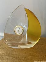 Front view of Bulova sailboat clock made of clear and yellow tinted crystal with a small round clock embedded in the clear sail.