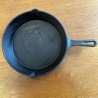 Top-down view of the cast iron frying pan showing the textured cooking surface and pouring spouts.