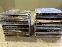 Two stacks of CDs showing album cover spines for identification and quantity verification.