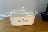 Rectangular white ceramic casserole dish with blue cornflower design on side, shown with clear glass lid on top.
