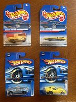 Set of 4 Hot Wheels cars in original sealed blister packaging on blue backing cards, displayed in a group layout.