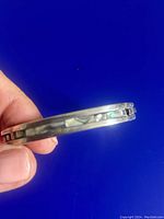 Side view showing the abalone inlay strip with iridescent colors inlaid on sterling silver hinged cuff bracelet