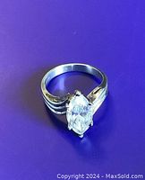 Silver ring with large marquise cut clear crystal stone on purple background.