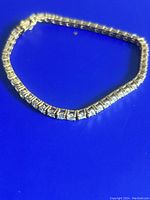 Sterling silver tennis bracelet laid out on blue background, showing full length and stone setting.