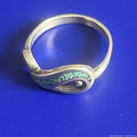 Sterling silver ring with turquoise mosaic inlay on a flat surface showing the entire ring and design details.