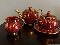 Full view of the vintage burgundy and gold Sudlow Burslem teapot set including teapot, sugar bowl with saucer, and creamer.