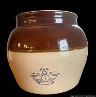 Vintage bean crock two-tone brown and beige with blue crown mark on front, no lid, shown on black background.