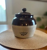 Front view of the vintage bean crock showing the blue crown symbol with number 2 on the beige part and dark brown top glaze with lid.