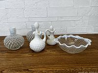 Five vintage Fenton hobnail opalescent glass items arranged on wood surface against white brick background, showing full lot contents.