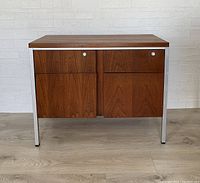 Front view showing the teak cabinet with metal frame, two drawers and two compartments below, in good vintage condition.