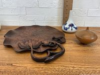 Front angle view showing the carved wooden platter with floral pattern, the porcelain vase with blue floral design and gold trim, and the wooden turned incense holder.