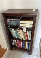 Front view loaded with books showing three shelves and carved posts