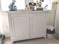 Front view of white wood cabinet with two doors and round knobs, showing overall condition and scratches.