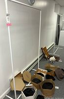 White metal clothes rack standing near wall in basement room with scattered boxes and other items on floor.