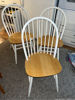 Three matching wooden dining chairs shown from front and side. White-painted spindles and legs with natural wood-colored seats.