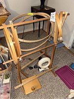 Full view of wooden needlepoint stand with several wooden embroidery hoops and magnifying light at the base.