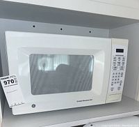 Front-left angle view of the white GE microwave oven showing control panel and window on door.