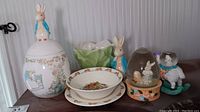 All items from the lot arranged on shelf, showing ceramic cookie jar, Bunnykins bowl and plate, plant pot, and Easter figurines.