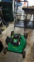 Full view of Weed Eater 22 inch green gas powered lawn mower with handle and wheels in garage