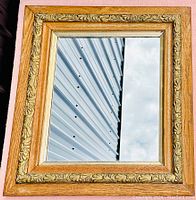 Front view of antique oak framed mirror showing full frame and reflection of background.