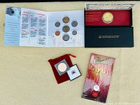 Full view of the lot including the proof-like coin set in booklet with polar bear image, black box with red backing containing a gold-colored coin, bronze medal in capsule with red pouch, and sealed Canada 2001 quarter package.