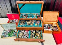 Overhead view of five jewelry storage containers and assorted costume jewelry pieces arranged on a surface