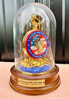 Full display showing the pocket watch enclosed in a glass dome with wooden base and brass plaque