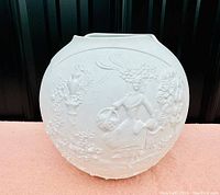 Front view of a white bisque porcelain vase with a raised relief design of a girl gathering roses in a garden.