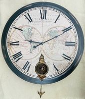Full front view of large round wall clock with world map dial and pendulum showing clock hands at 9:18.