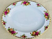 Top view of white bone china Old Country Roses oval platter with floral pattern of red, pink, and yellow roses with green leaves and gold rim.