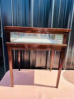 Side view of vintage wood display case side table showing tapered legs and glass panels.