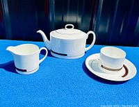 Full set of Wedgwood Susie Cooper Prelude teapot, creamer jug, and sugar bowl displayed on a blue cloth.