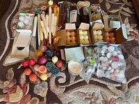 Photo of assorted candles, including boxed Party Lite tea light candles, loose tea lights in multiple colors, and taper candles, arranged on a patterned carpet.
