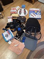 Photo showing multiple home health care items arranged on floor including several black support braces, a pink electric heating pad with cord, two blue massage balls, a gray foot pad, and boxed Dr. Ho circulation promoter kit.