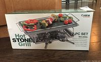 Photo of the unopened Cuisine Essentials Hot Stone Grill 7-piece set box showing product image and branding.
