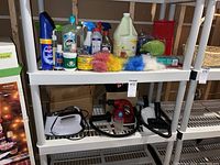 Shelf showing various household cleaning supplies including sprays, polishes, dusters, and cleaning bottles