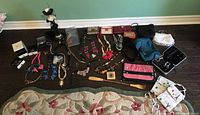 Top-down view of all jewelry pieces, wallets, and the black jewelry stand arranged on wooden floor.