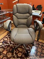 Front view of gray upholstered office chair showing padded seat, backrest, and armrests.