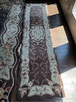 Pair of two brown and beige wool runner rugs laid side by side on a wooden floor, showing floral patterned borders and main brown field.
