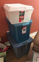 Photo of three stacked plastic storage totes showing a clear white tote, a blue Rubbermaid tote, and a gray tote.