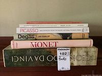 Stack of five art-related books including Picasso, Degas, Monet, Leonardo da Vinci, and an antiques magazine, showing condition and titles.