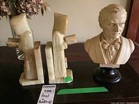 View of the two onyx bookends and plastic Wagner bust on table, showing damage and loose pieces.