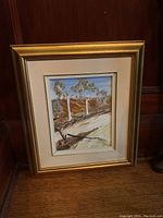 Framed original acrylic painting depicting a landscape with trees and a dirt path, housed in a gold frame with cream double matting, showing clear artist signature.