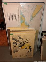 Overview photo showing multiple prints and posters mounted on boards stacked vertically including a large chart/map and a Confetti print