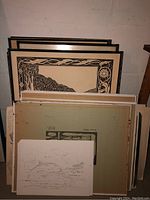 Stack of various artistic and decorative prints including black and white and line illustrations.