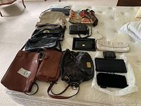 Full overview of 14 assorted purses, clutches, coin pouch, and tote bag arranged on a bed.